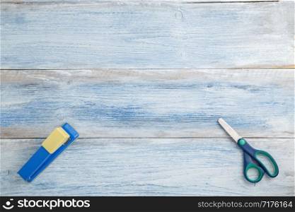 scissors and stapler on a blue and white shabby vintage wooden background. the view from the top. Flat lay
