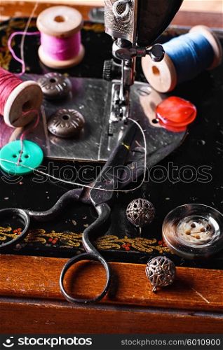 Scissors,button and thread on the background of the sewing machine the old model
