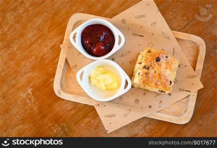 scones and jam on wooden plate, served scones and cream for dessert and tea - fresh homemade butter scones - top view