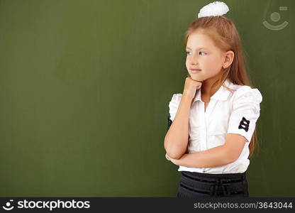 Scoolgirl standing in class near a green blackboard