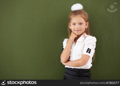 Scoolgirl standing in class near a green blackboard