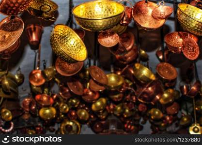 Scoop and soup ladles recycled used as ornament and decorations hanging from the ceiling. Bronze and golden scoops hang from the roof inside a house.. Scoop and soup ladles recycled used as ornament and decorations hanging from the ceiling. Bronze and golden scoops hang from the roof.