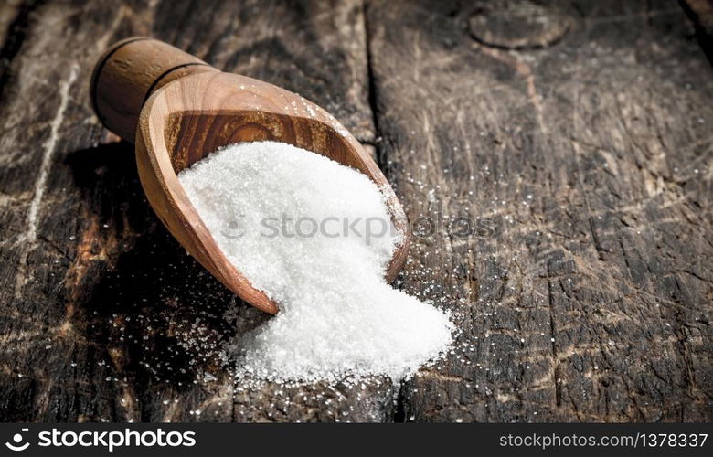 Scoop with sugar. On a wooden background.. Scoop with sugar.