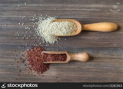 Scoops of raw white and red quinoa on the wooden background