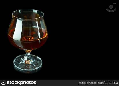 Scotch drink on black background. Old fashioned whiskey glass as loneliness symbol. Unhealthy still life or bad habits concept. Clear brandy or bourbon snifter.. Scotch drink on black background