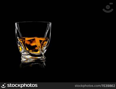 Scotch whiskey in crystal modern luxury glass on black background with reflection. Space for text