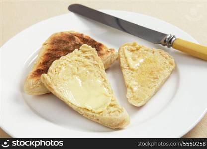 Scottish girdle (griddle) scones, one sliced and buttered, on a white plate - a very traditional north British dish.