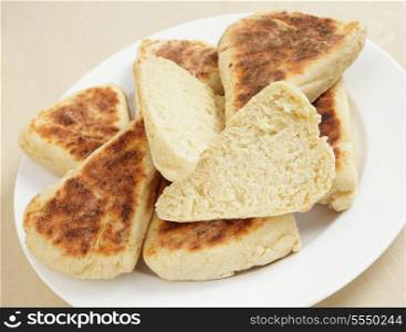 Scottish girdle scones on a plate, with one of them sliced in half to show the texture