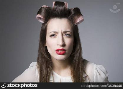 Scowling young woman with hair curlers and red lipstick