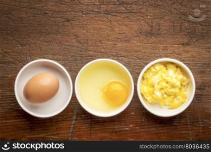 scrambled egg abstract - white bowls with eggs against rustic, weathered wood with a copy space