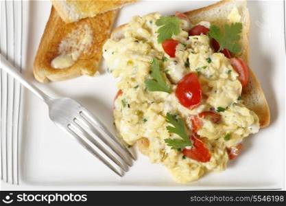Scrambled egg on toast with cherry tomatoes, parsley and pepper. Cooking in a bain marie allows the tomatoes to be incorporated rather than curdling. From above