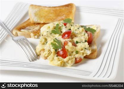 Scrambled egg on toast with cherry tomatoes, parsley and pepper. Cooking in a bain marie allows the tomatoes to be incorporated rather than curdling.