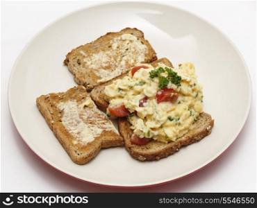 Scrambled egg on whole-grain toast with parsley and cherry tomatoes,