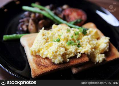 scrambled egg with bread and mushroom on wood background