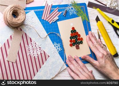 scrapbook background. Girl make christmas postcard from buttons and tools with decoration