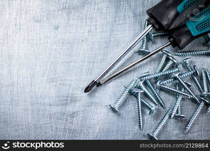 Screwdrivers with self-tapping screws on the table. On a gray background. High quality photo. Screwdrivers with self-tapping screws on the table.