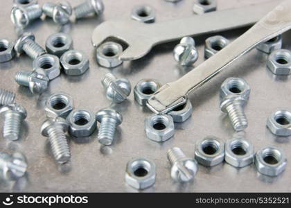 screws with nuts and wrench on the metal plate