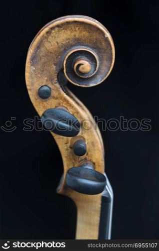 scroll part of violin against black background in closeup