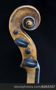 scroll part of violin against black background in closeup