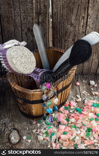 Scrub,brush,nail file in wooden tub on the background scattered with sea salt for Spa treatments.