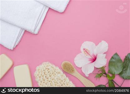 scrub glove brush hibiscus flower soap towel pink background