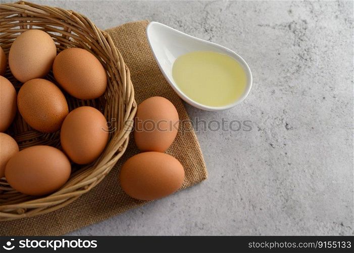 Se≤ctive focus eggs on sack cloth, many eggs on wicker basket and oil in bowl placed on the floor, preparing for cooking food or dessert,©space