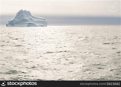 Sea and ocean landscape in greenland with dramatic sky, sun light, and iceberg