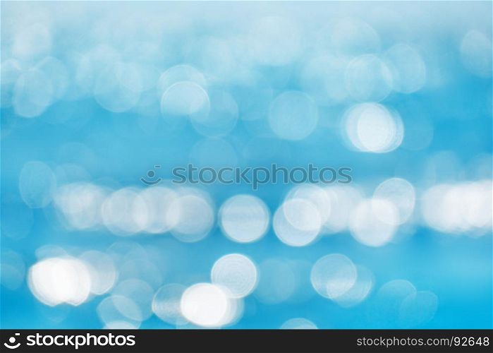 Sea blurred bokeh background with patches of light from the sun.