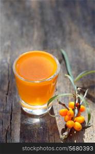 Sea buckthorn juice and berries isolated on wooden background. Natural detox.