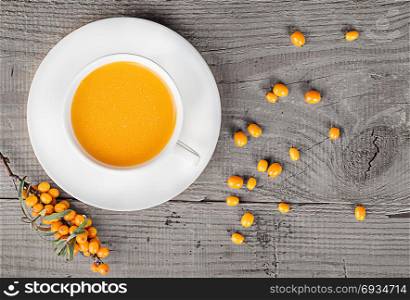 Sea buckthorn juice on a wooden table. A branch of sea-buckthorn and berries top view.