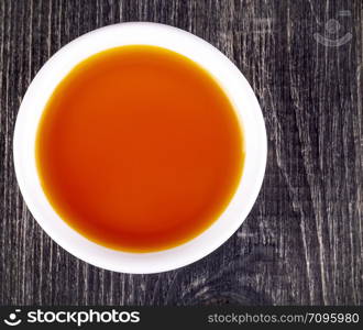 sea buckthorn oil in the white small Cup on old wooden background