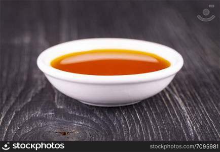 sea buckthorn oil in the white small Cup on old wooden background