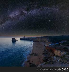 Sea coast night view with Lighthouse of Ponta do Altar and starry Milky Way in sky. West view over Praia da Afurada beach (Ferragudo, Lagoa, Algarve, Portugal).