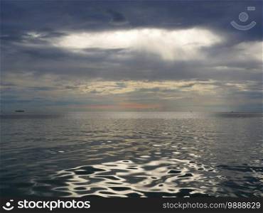 sea dramatic landscape with rays through a cloudy dark sky