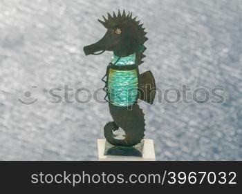 Sea horse made of metal and green glass on the parapet of the embankment in Fira. Greece. Santorini.. Metal statue of seahorse in Fira.