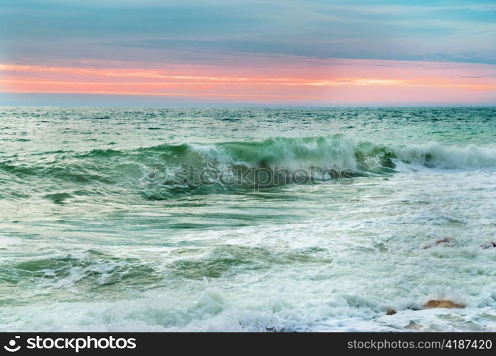 Sea landscape with big waves against sunset