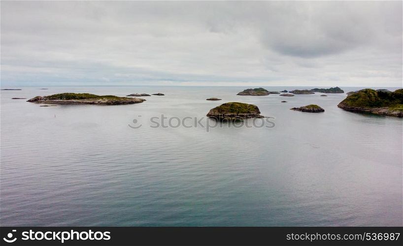 Sea landscape with islets among the waters of fjord Vjestfjord, Lofoten islands, Henningsvaer region, Norway. Hazy day, overcast weather.. Aerial view. Lofoten islands landscape, Norway