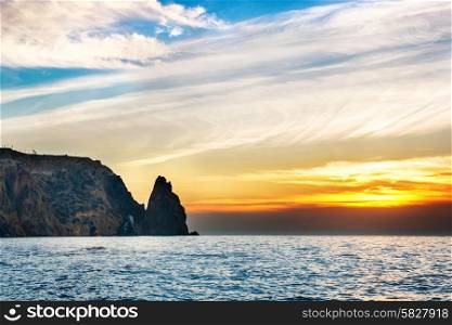 Sea landscape with sunset over rocks and dramatic sky