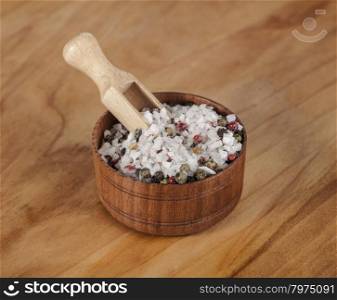 Sea salt and black peppers balls. Large sea salt with red and black pepper in a wooden jar with a small wooden spoon on a beautiful wooden tray .