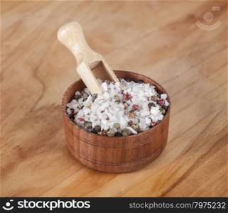 Sea salt and black peppers balls. Large sea salt with red and black pepper in a wooden jar with a small wooden spoon on a beautiful wooden tray .
