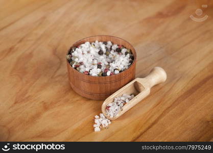 Sea salt and black peppers balls. Large sea salt with red and black pepper in a wooden jar with a small wooden spoon on a beautiful wooden tray .