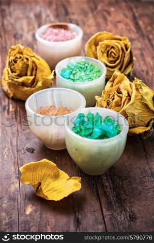 sea salt for body care. sea salt for Spa treatments with ceramic cups on the background of the buds dried yellow roses