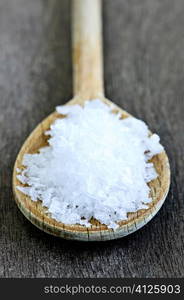 Sea salt on wooden spoon over wooden table background