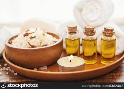 Sea salt, towels, aroma oil in bottles and flowers on vintage wooden background. Selective focus.