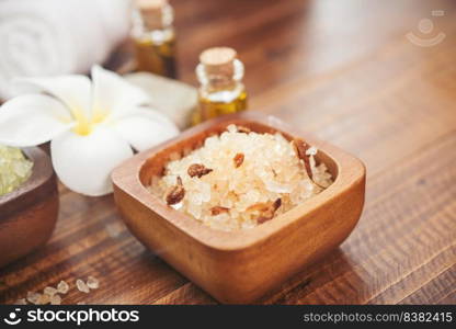 Sea salt, towels, aroma oil in bottles and flowers on vintage wooden background. Selective focus.