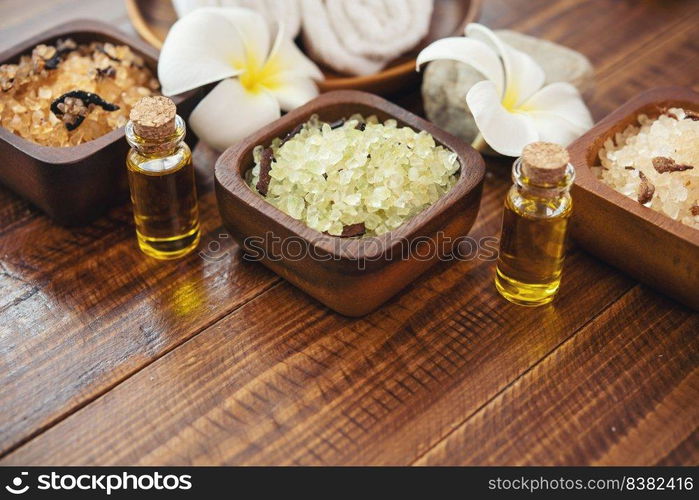 Sea salt, towels, aroma oil in bottles and flowers on vintage wooden background. Selective focus.