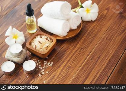 Sea salt, towels, aroma oil in bottles and flowers on vintage wooden background. Selective focus.