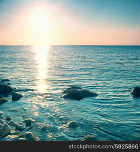 Sea shore and stones at sunset. Seascape with shining sun