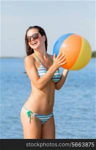 sea, summer vacation, holidays, sport and people concept - smiling teenage girl sunglasses with inflatable ball on beach