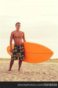 sea, summer vacation, water sport and people concept - smiling young man with surfboard on beach